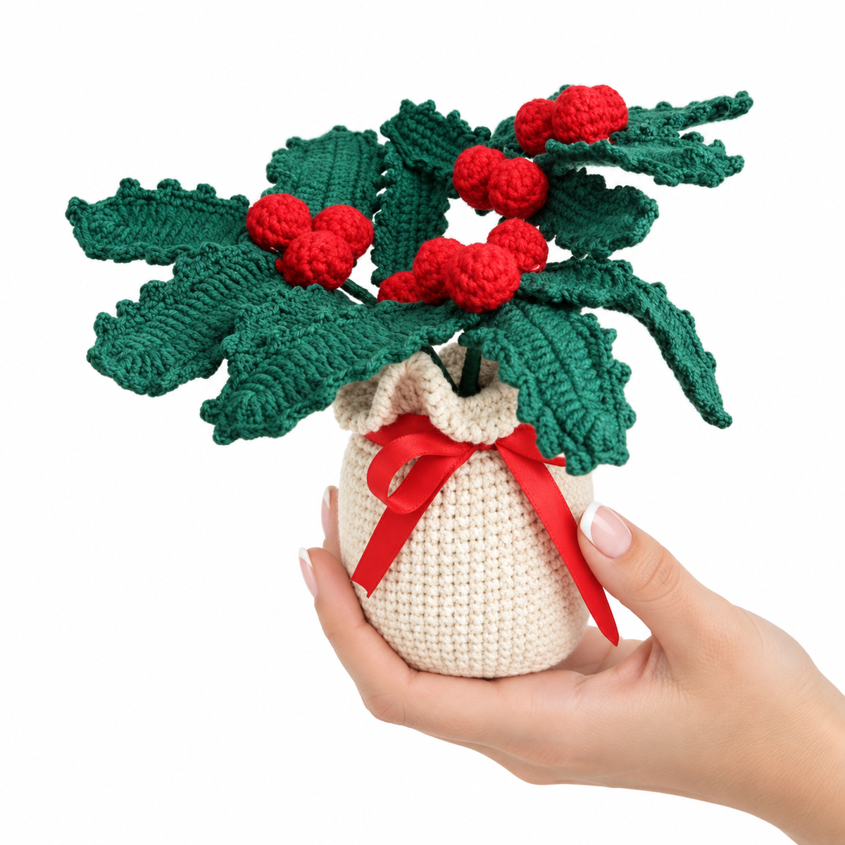 Crocheted potted holly plant decor, green leaves with red berries, tied red ribbon on cream pot