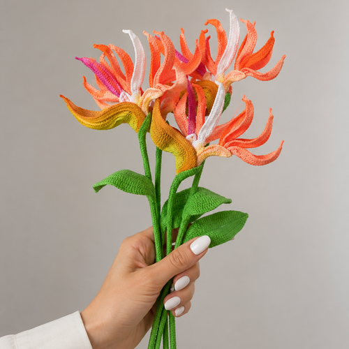 Crochet bird of paradise flower bouquet held in hand, orange and yellow petals with green stem