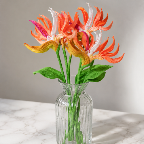 Crochet bird of paradise bouquet in glass vase, orange and white petals with green leaves