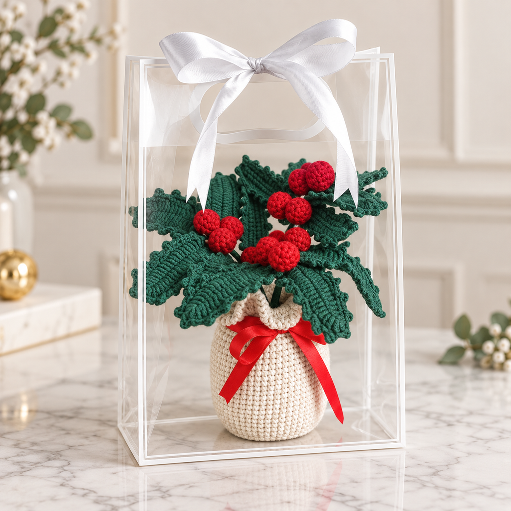 Crocheted potted holly plant decor in clear gift box, green leaves, red berries, red ribbon