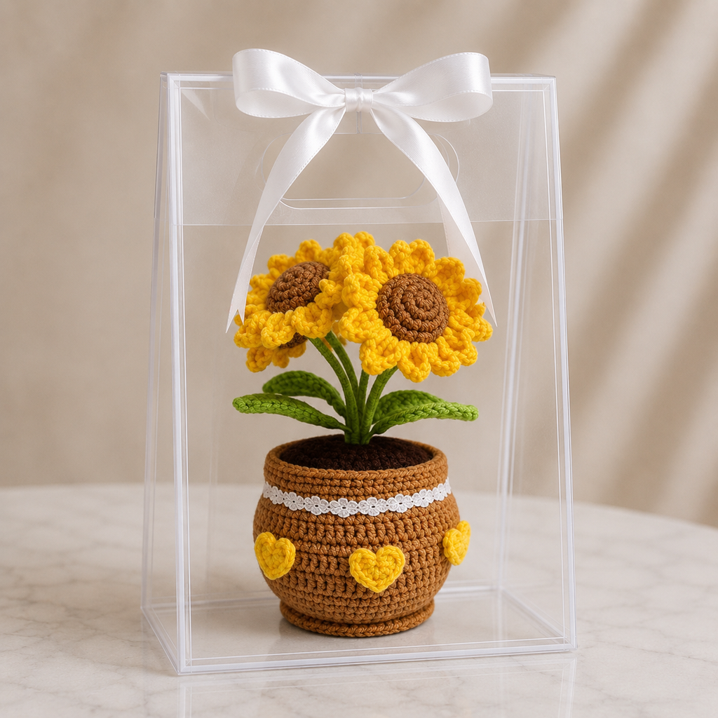 Crocheted potted sunflower plant in clear gift box with white ribbon, yellow blooms