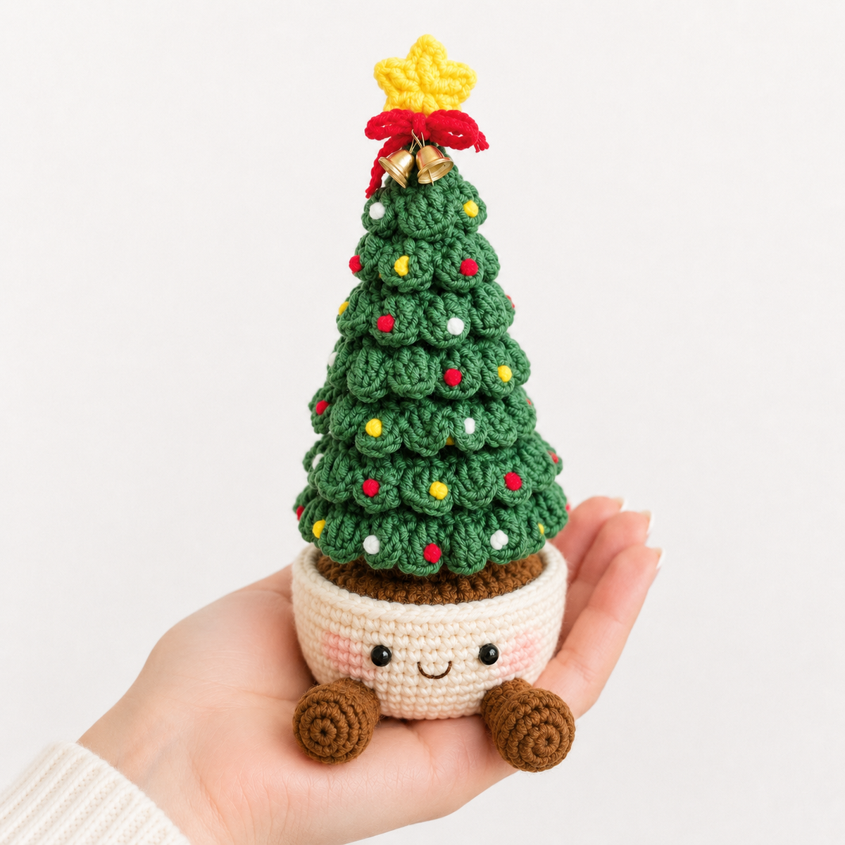 Crochet Christmas tree ornament with green layered yarn and smiling cream pot base, bow topper