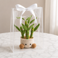 Handmade crochet potted plant with green cacti stems and a beige pot with cute face