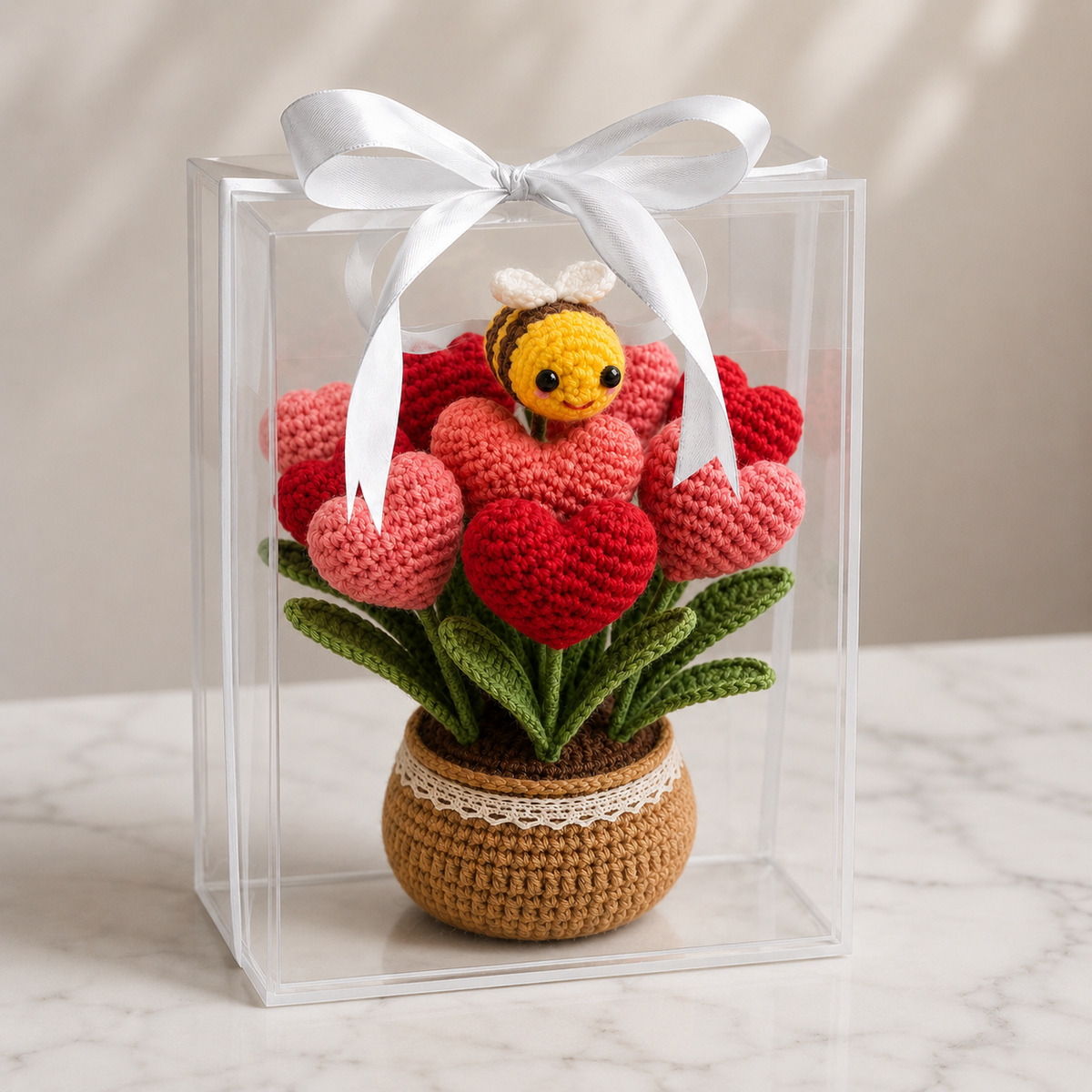 Crochet heart flower pot with bee, red heart blossoms, green leaves in clear gift box