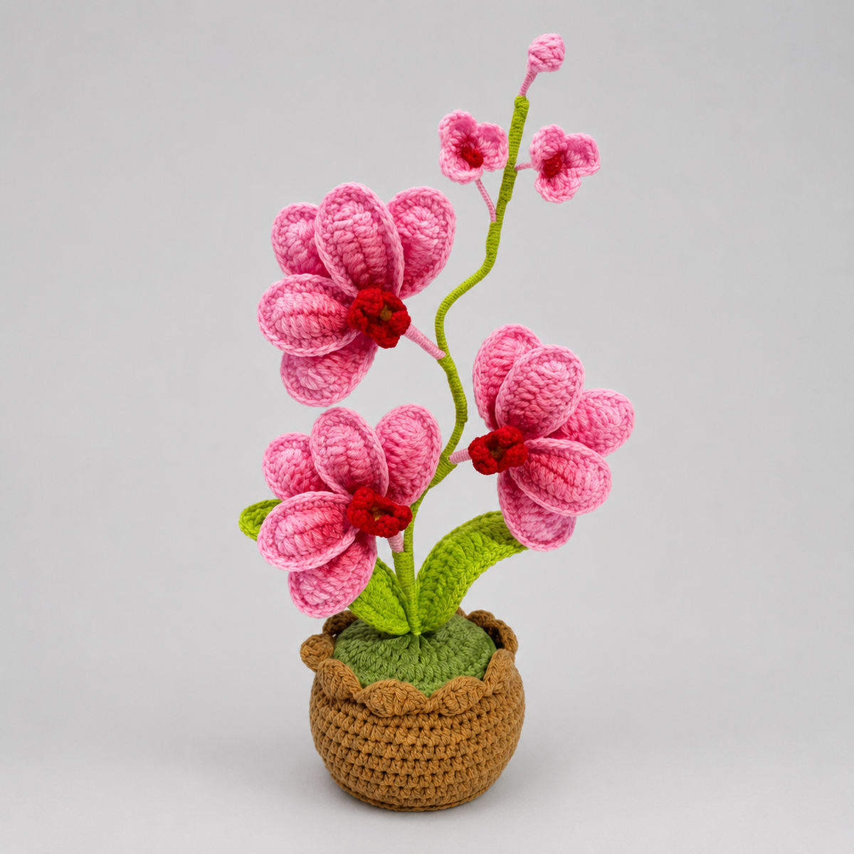 Handmade crochet orchid with pink blossoms in a small brown crocheted pot