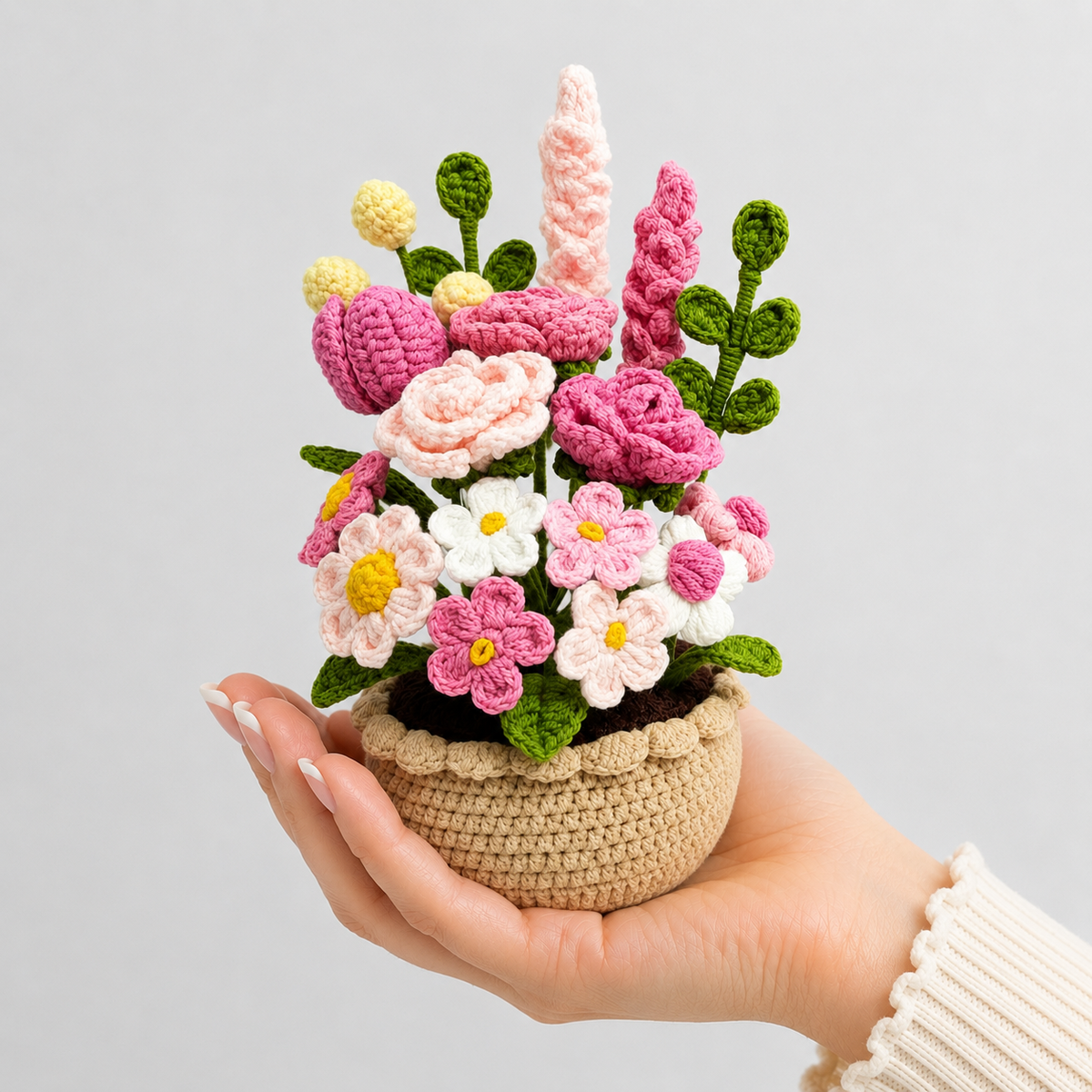 Crochet wildflower amigurumi bouquet in beige pot, held in a person’s hand