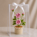 Crochet rose flower in beige pot with pink blooms, in clear gift box with white bow