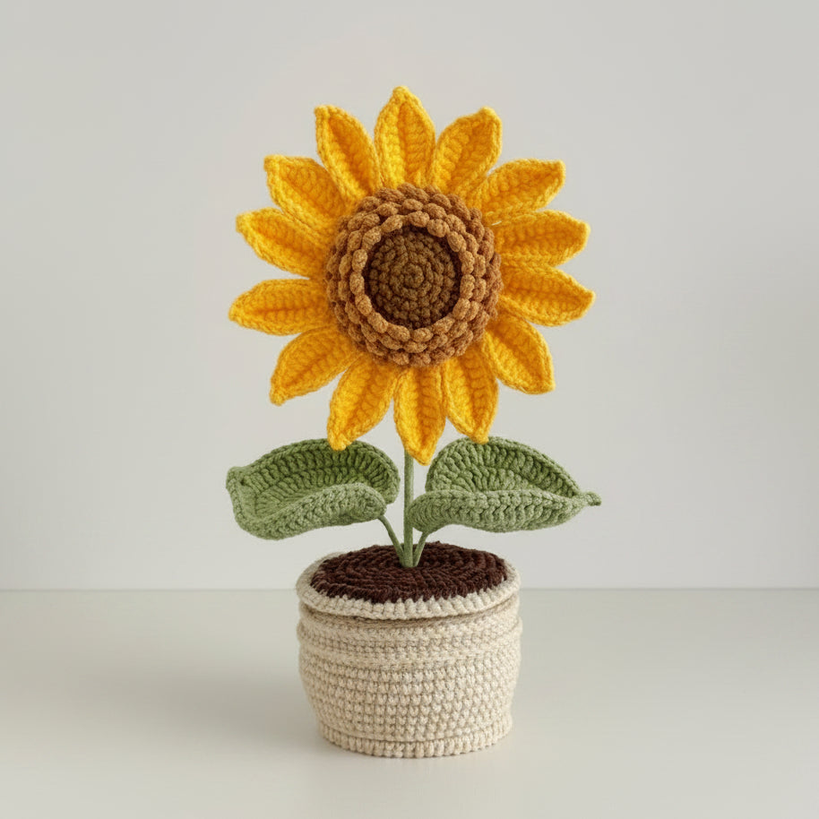 Handmade crocheted sunflower in a small fabric pot, with brown center and green leaves.