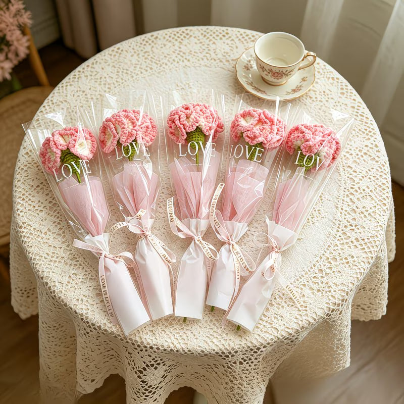 Set of crocheted pink carnation single-stem bouquets in clear wrap with pink ribbons