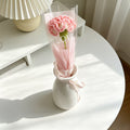 Crocheted pink carnation single-stem bouquet in clear wrap with pink ribbon
