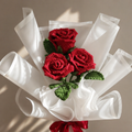 Handmade crocheted rose bouquet with red flowers, green leaves, white wrap, red satin bow